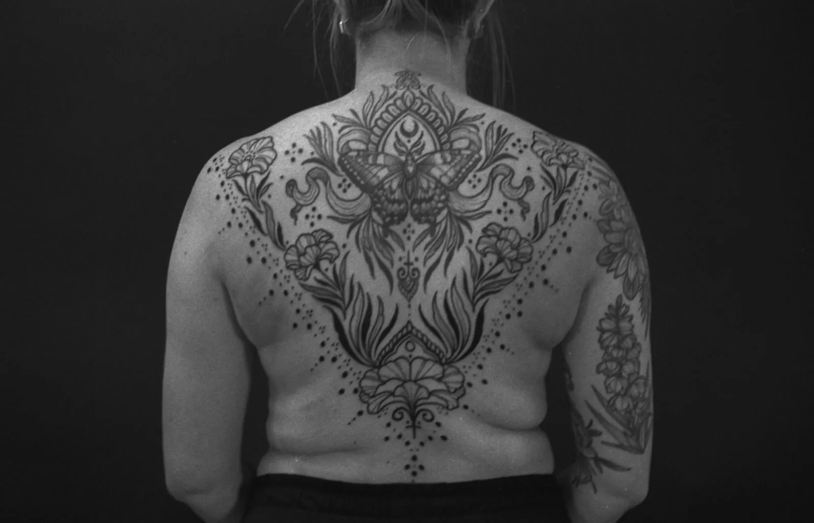 Ornamental backpiece with a moth and flowers across the upper back